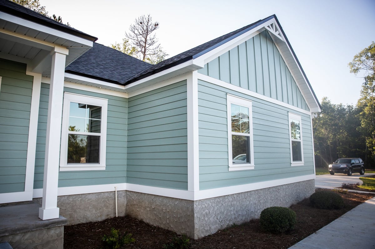 A freshly completed ranch home with new blue siding and a tidy yard