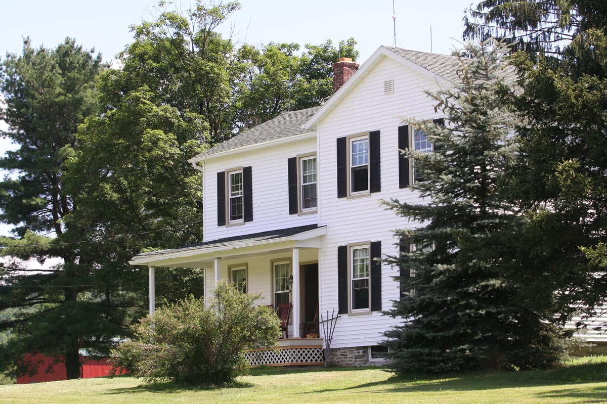 A classic farmhouse with white clapboard siding and black shutters